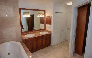 bathroom with double sinks and large mirror, bathtub