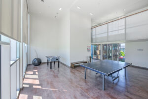 Interior Recreation Room, Table Tennis, foosball table, wood 2 benches, large contemporary potted plant, floor to ceiling windows, landscape art on walls.