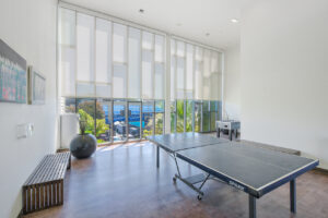 Interior Recreation Room, Table Tennis, foosball table, wood 2 benches, large contemporary potted plant, floor to ceiling windows, landscape art on walls.